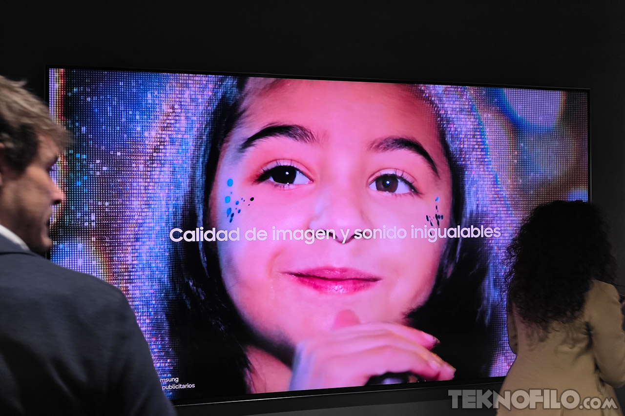 Pantalla grande mostrando a una niña, texto Calidad de imagen y sonido inigualables. Dos personas cerca miran.