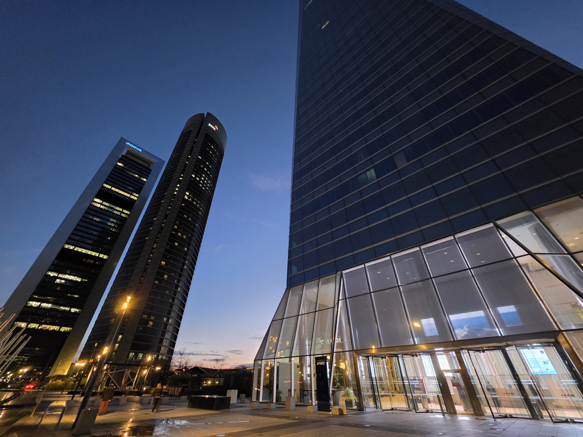 Torres altas en una ciudad al anochecer, con iluminación urbana y cielo azul oscuro.