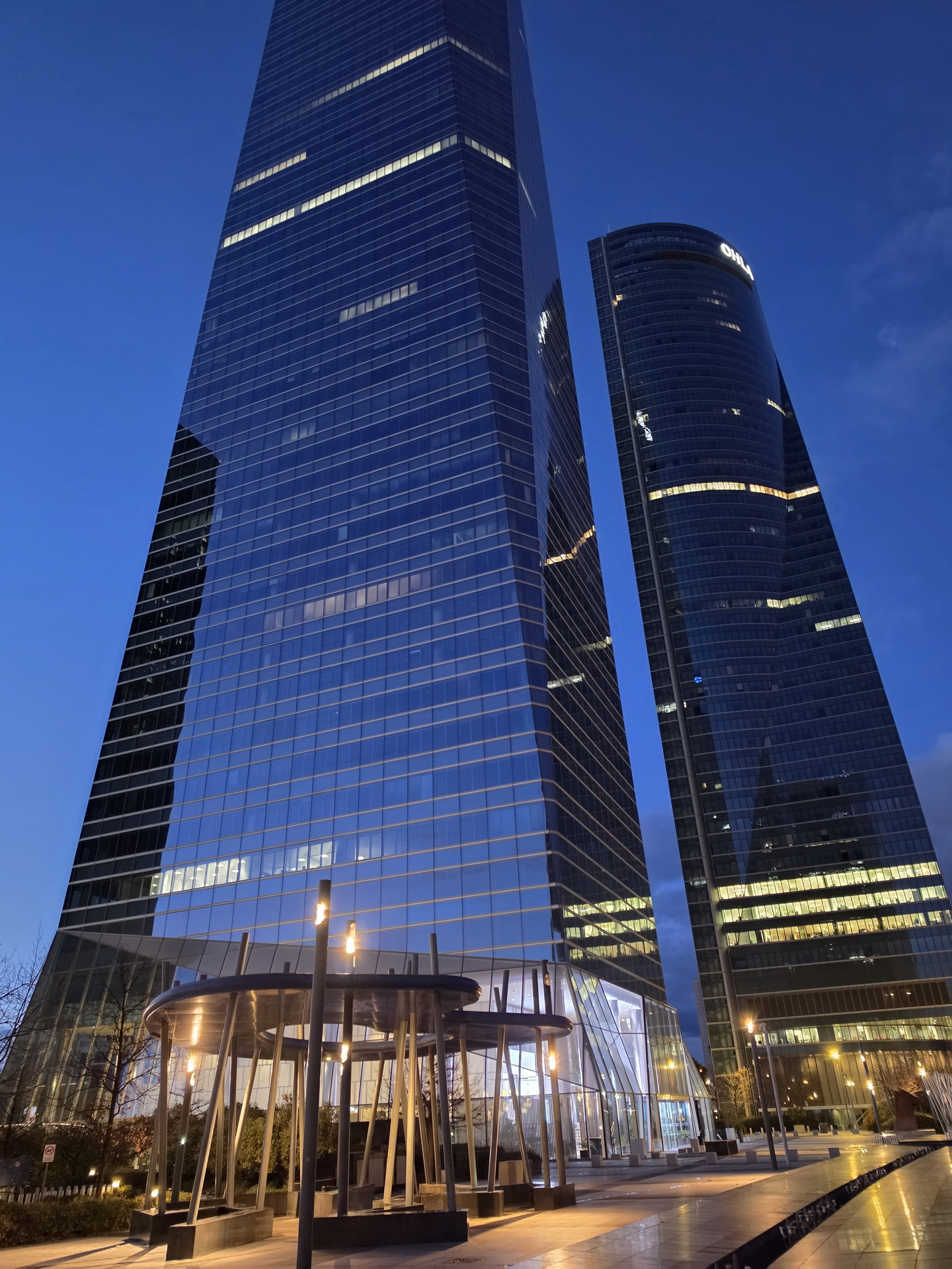 Rascacielos modernos al atardecer en un distrito financiero, reflejando el cielo azul oscuro.