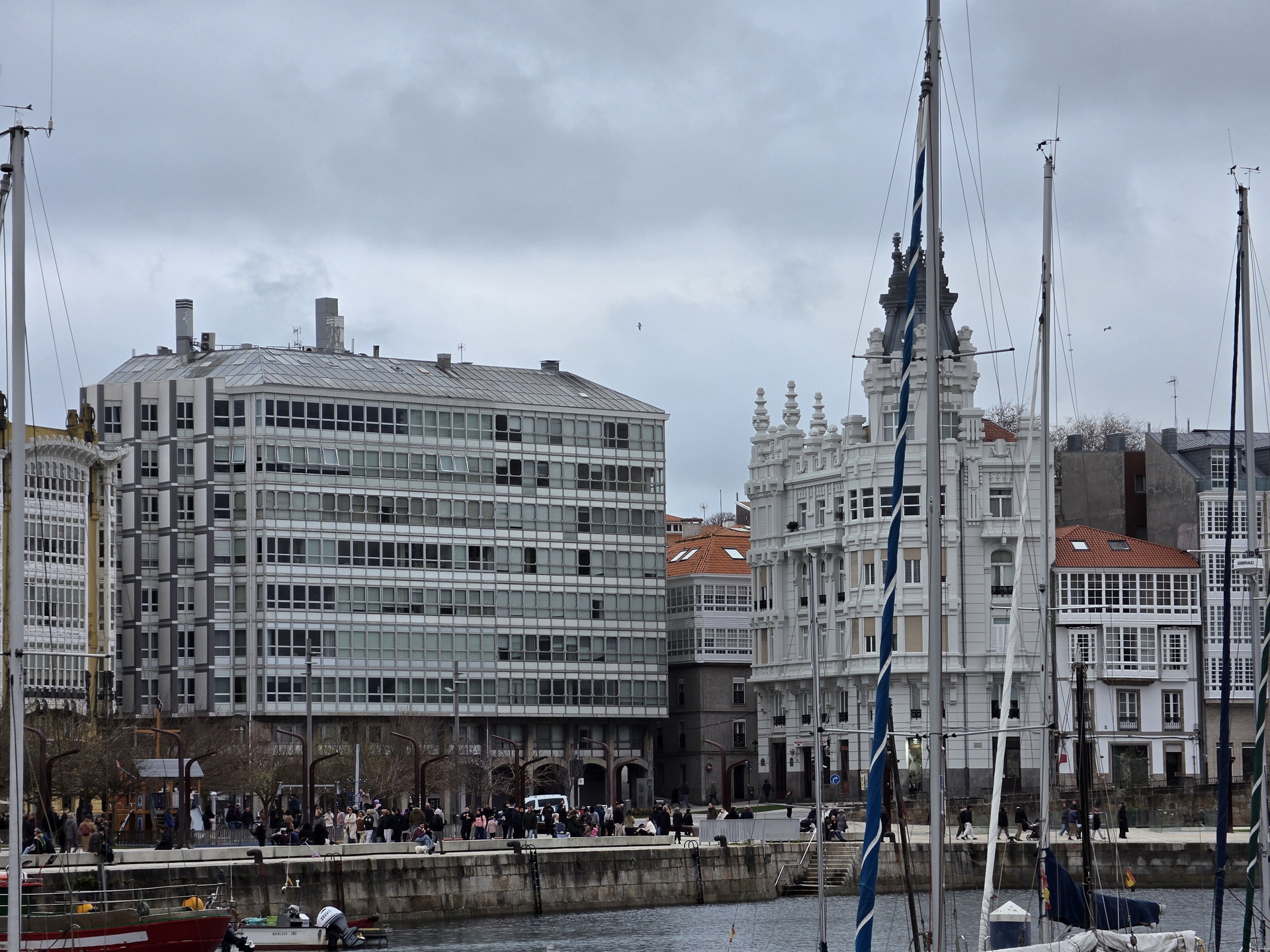 Puerto y arquitectura en A Coruña, edificios con galerías acristaladas y barcos en el muelle, cielo nublado.