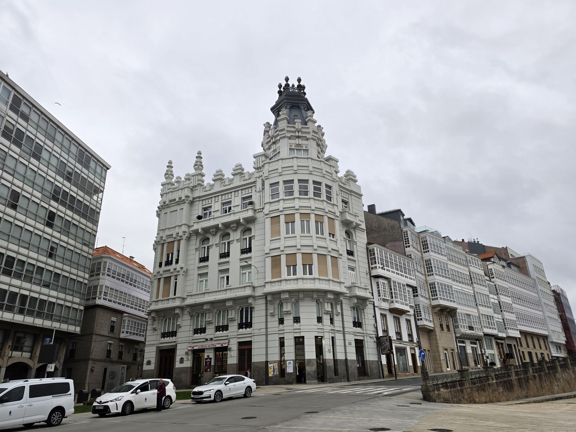 Edificio histórico en A Coruña con arquitectura clásica y galerías acristaladas, cielo nublado al fondo.