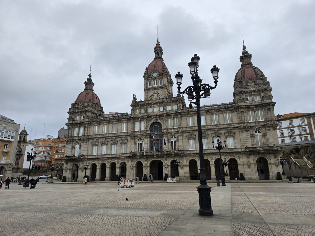 Edificio histórico en plaza céntrica de A Coruña, Galicia, con cielo nublado.