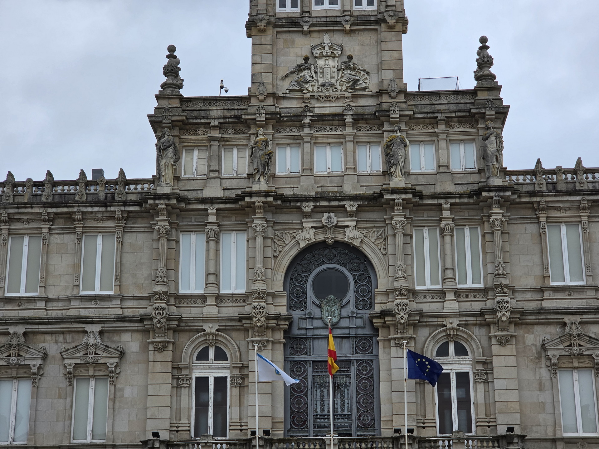 Fachada del edificio del ayuntamiento de A Coruña con banderas de España y la Unión Europea ondeando.