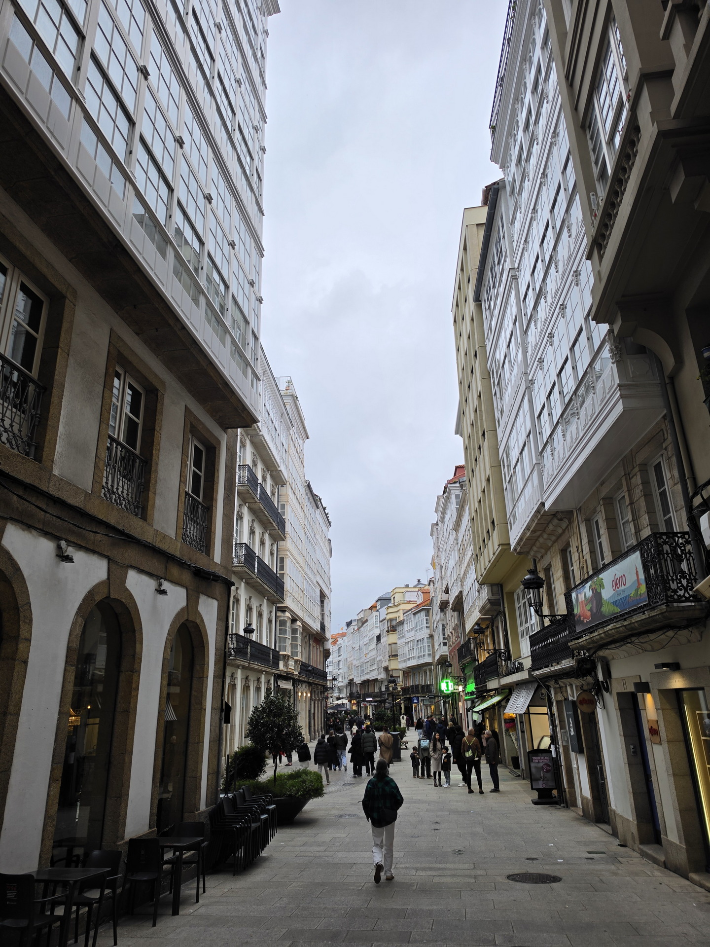 Calle peatonal en una ciudad con edificios altos de galerías y transeúntes paseando.