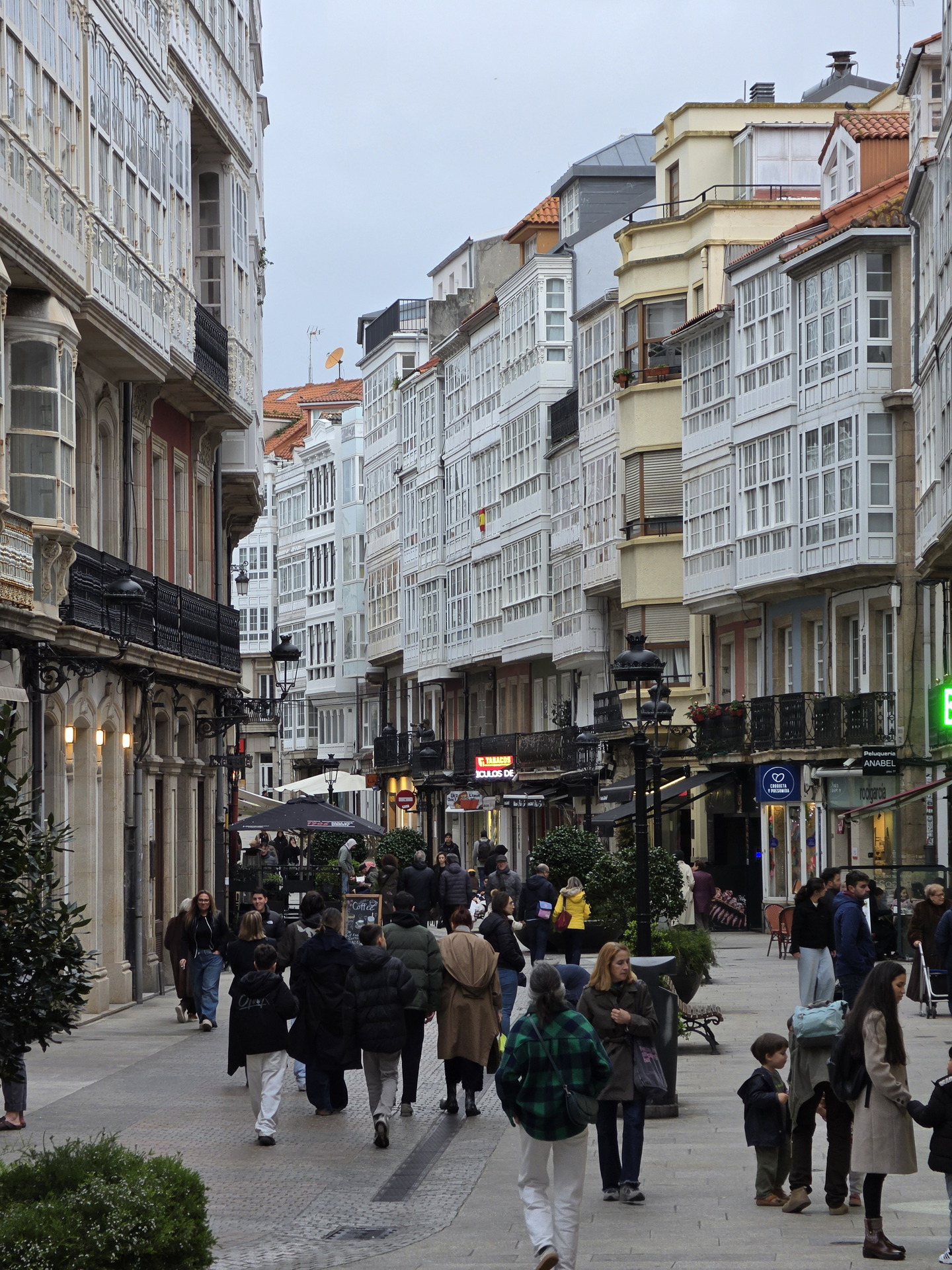 Calle peatonal en ciudad española con edificios históricos y gente paseando, Galicia, arquitectura única.