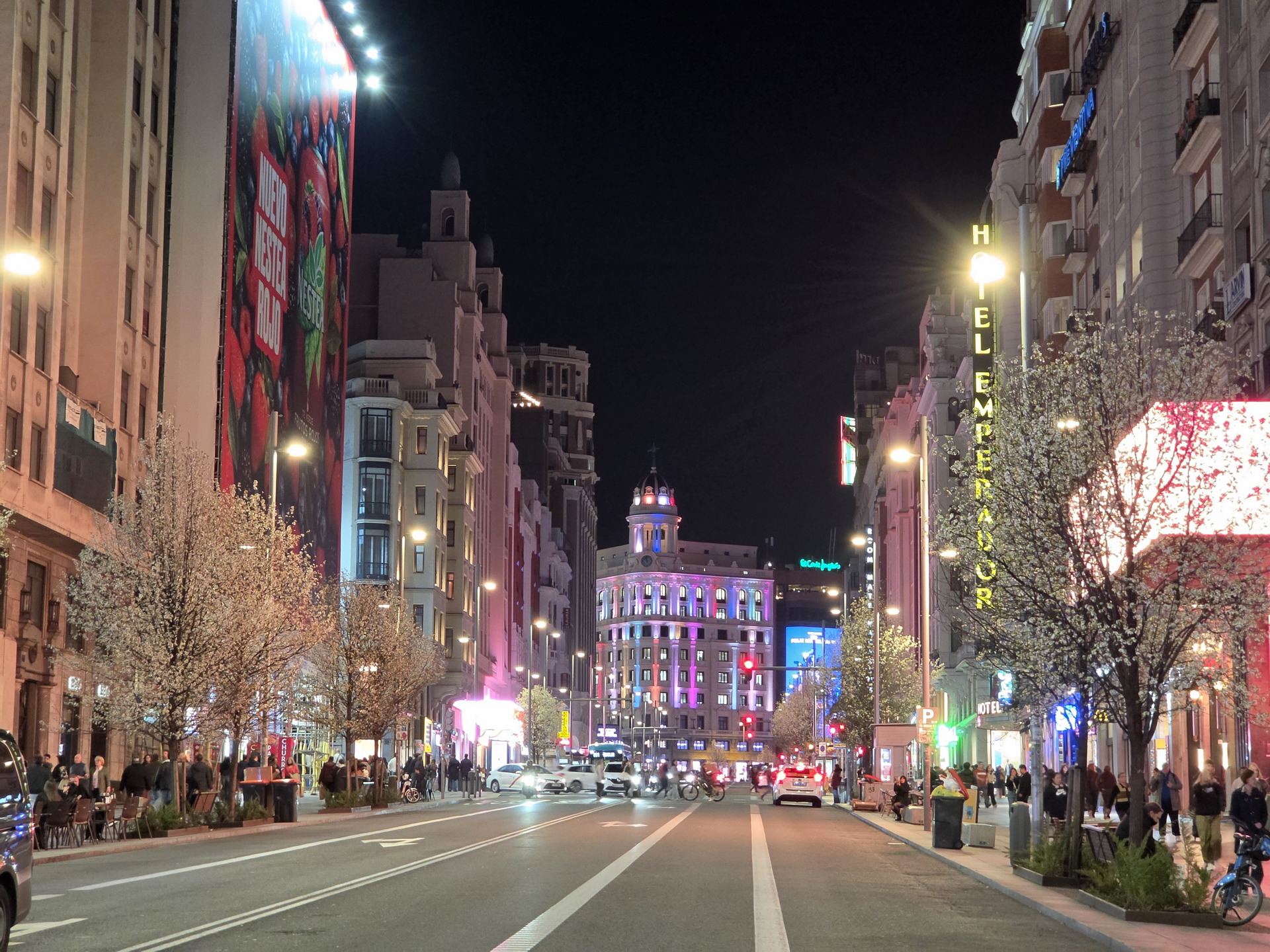 Calle iluminada de noche en Madrid con edificios y luces de neón, muestra un ambiente vibrante y urbano.