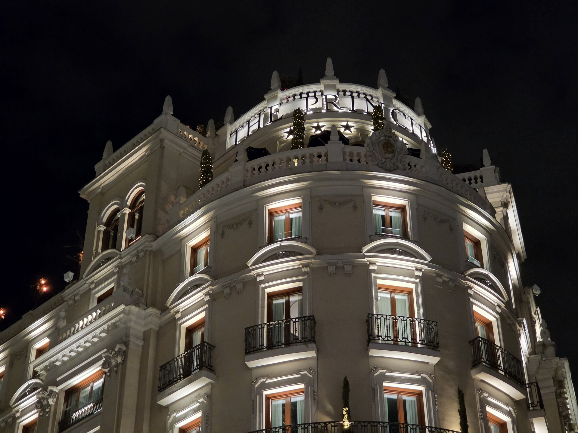 Edificio iluminado de noche, destaca la arquitectura elegante con balcones y decoraciones clásicas.