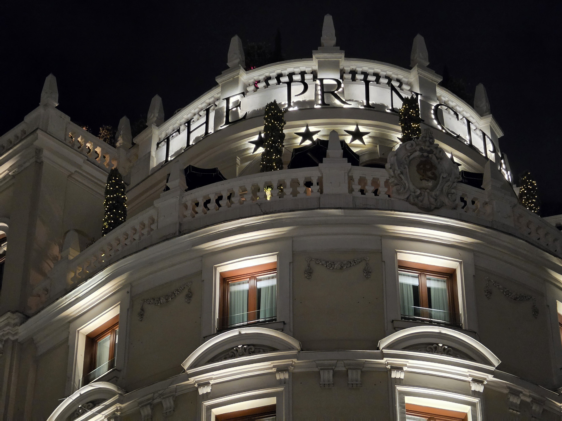 Fachada iluminada de edificio histórico decorado con luces, situado en una ciudad, visto de noche.