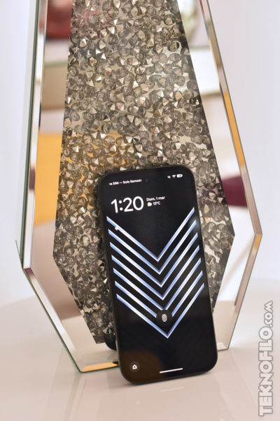 Teléfono móvil con pantalla cargada frente a fondo decorativo geométrico.