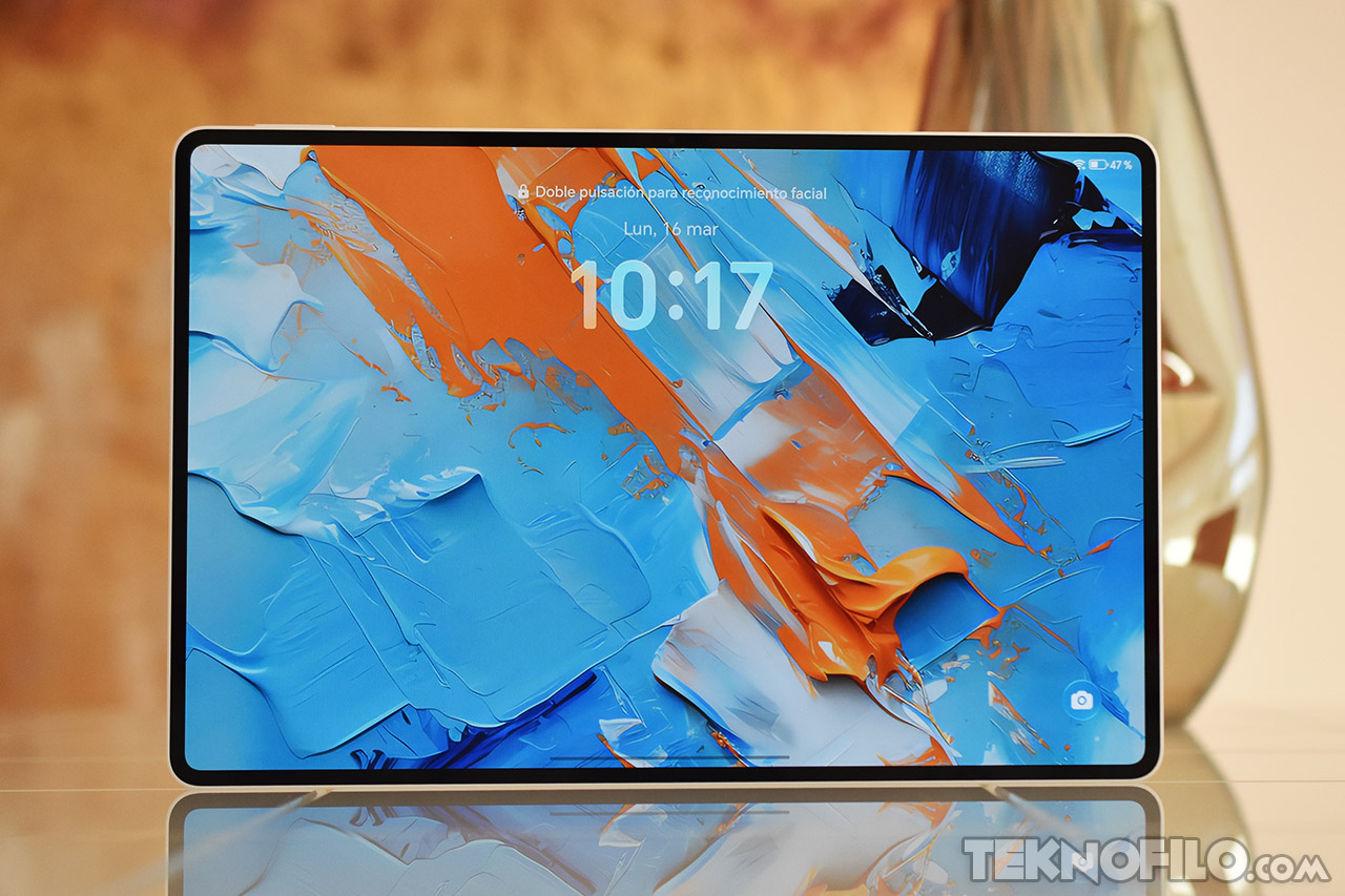 Pantalla de tablet con fondo azul y naranja abstracto, mostrando la hora 10:17. Tecnología moderna de reconocimiento facial.
