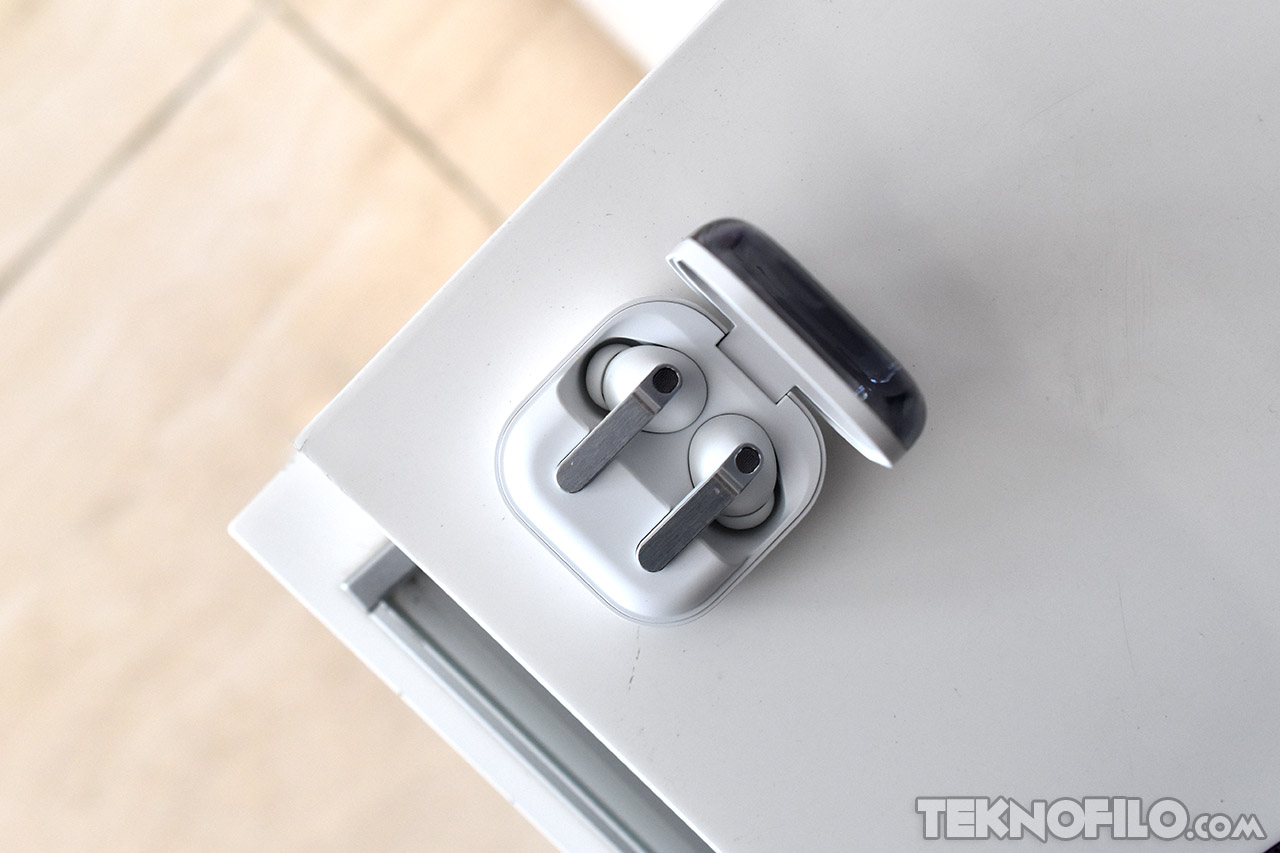 Auriculares inalámbricos en estuche blanco abiertos sobre una mesa clara.