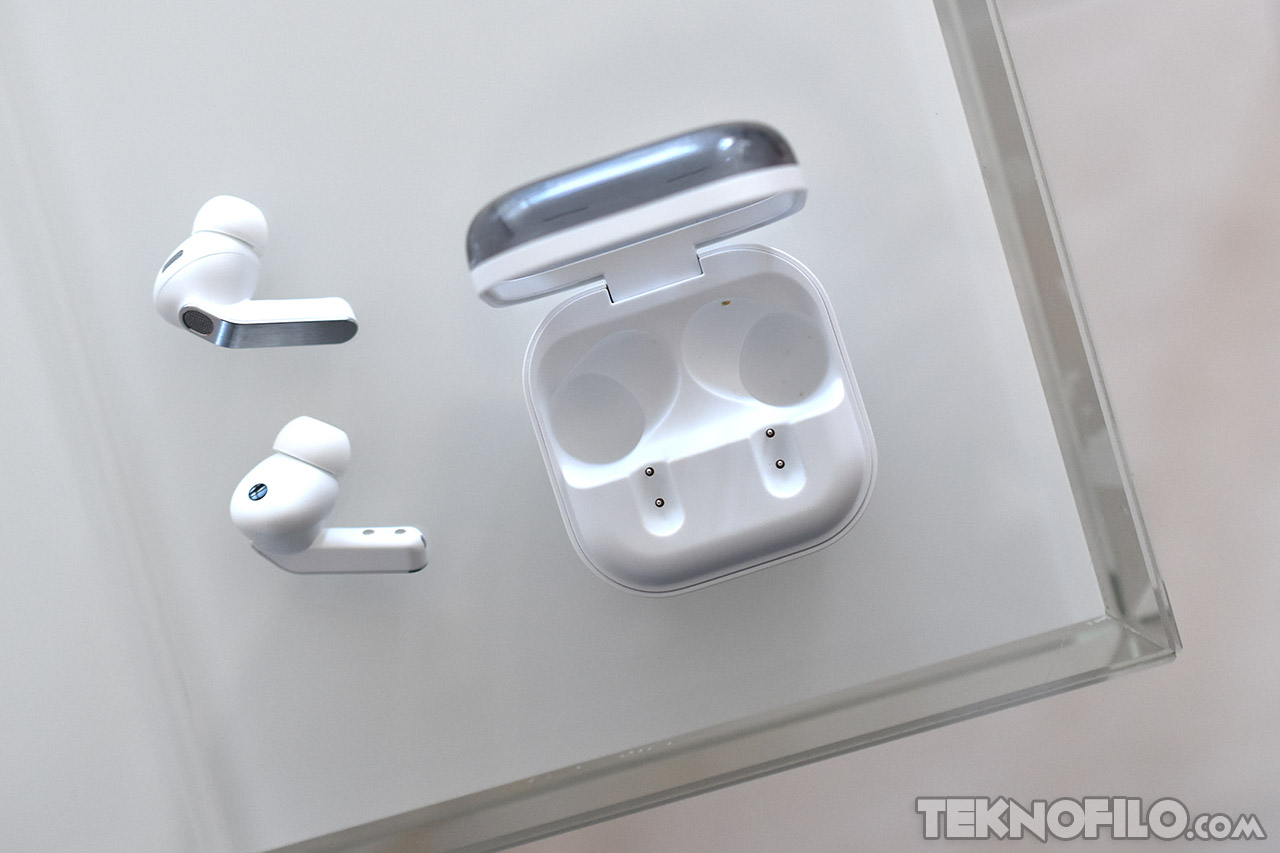 Auriculares inalámbricos blancos y estuche de carga en mesa de vidrio. Tecnología moderna y elegante diseño.