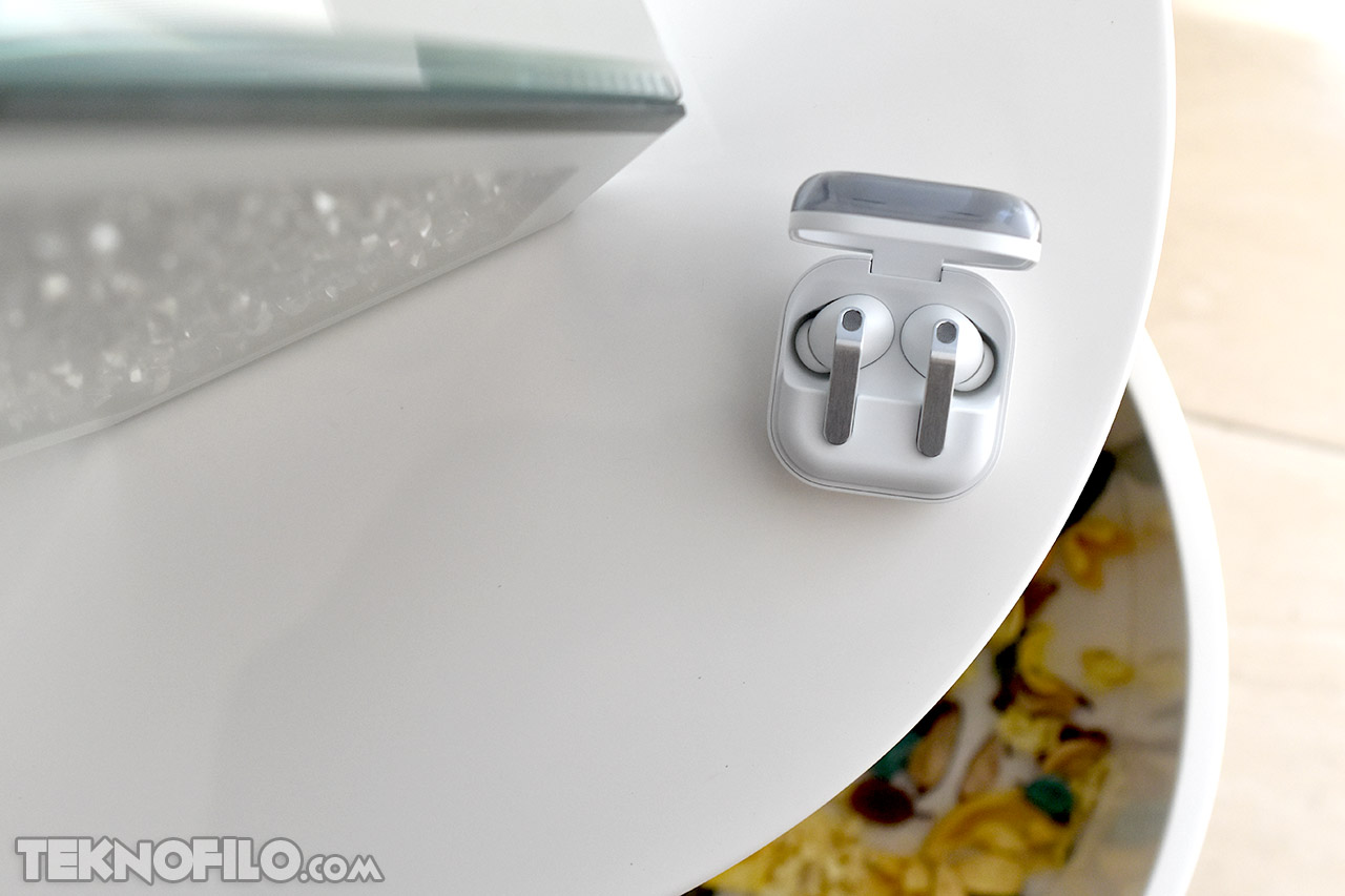 Auriculares inalámbricos en estuche de carga sobre mesa blanca. Tecnología moderna y minimalista.