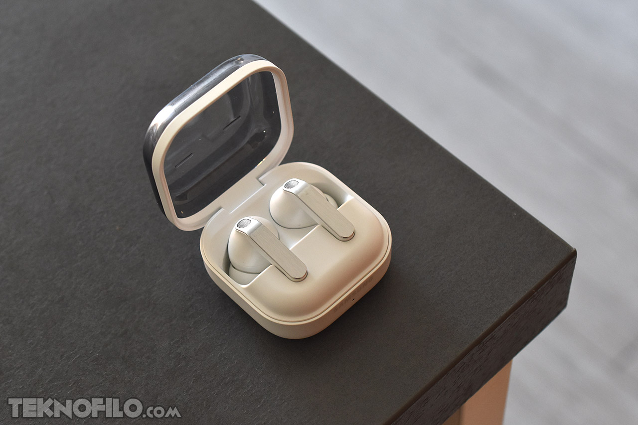 Auriculares inalámbricos blancos en estuche abierto sobre mesa negra, tecnología de sonido portátil innovadora.