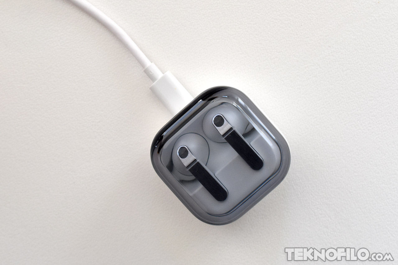 Cargador de AirPods Pro, enchufado y visto desde arriba, sobre superficie blanca.