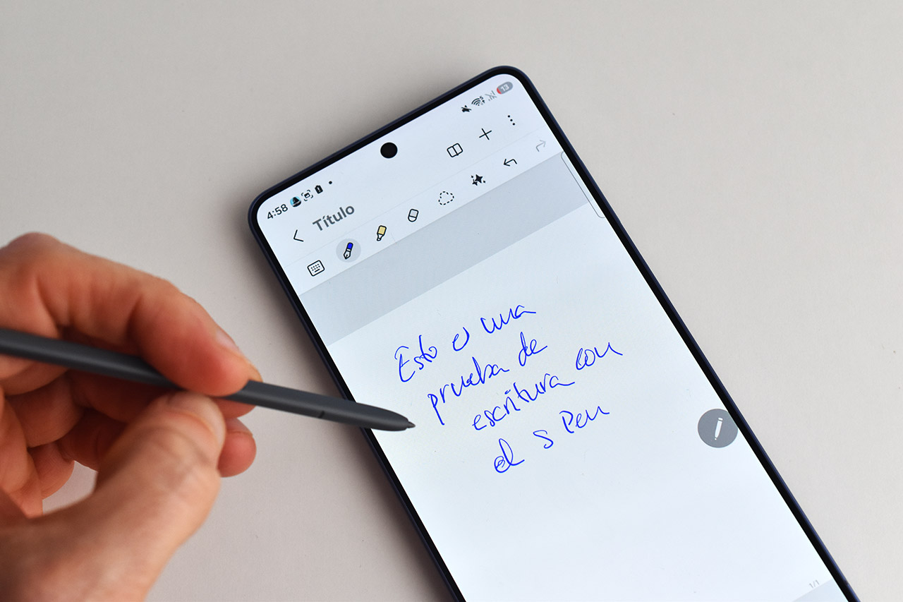 Mano escribiendo con un S Pen en un smartphone, mostrando una nota digital.