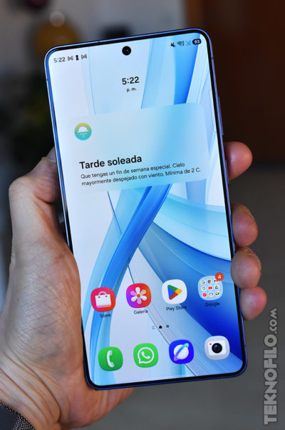 Smartphone con pantalla encendida mostrando aplicaciones y notificación de clima soleado. Hora: 5:22 p.m.