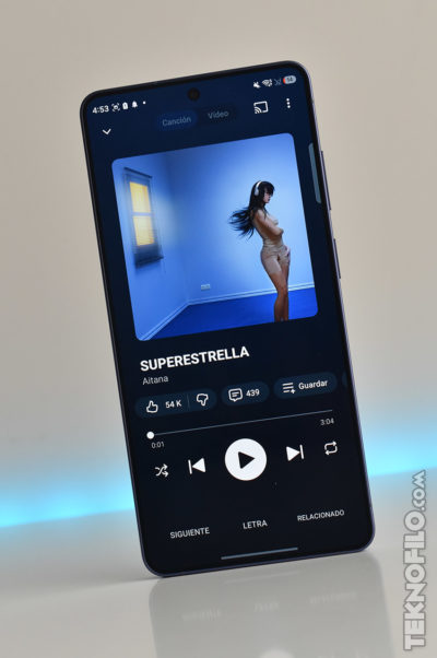 Smartphone mostrando canción Superestrella de Aitana en su pantalla, con opciones de reproducción y calificación.