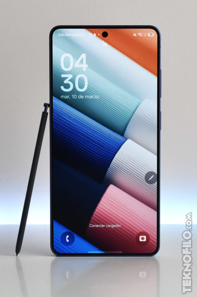 Teléfono inteligente con pantalla encendida y lápiz óptico apoyado al lado, mostrando hora y fecha.