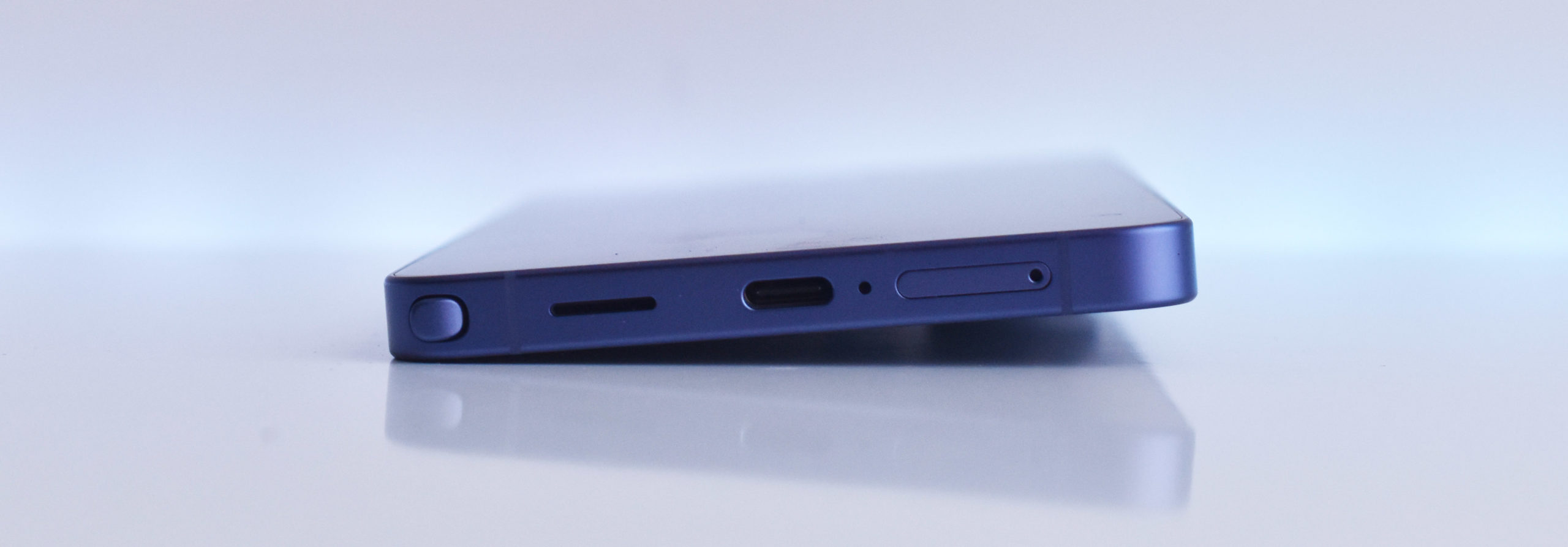 Puerto de carga USB-C en un smartphone azul sobre fondo blanco.