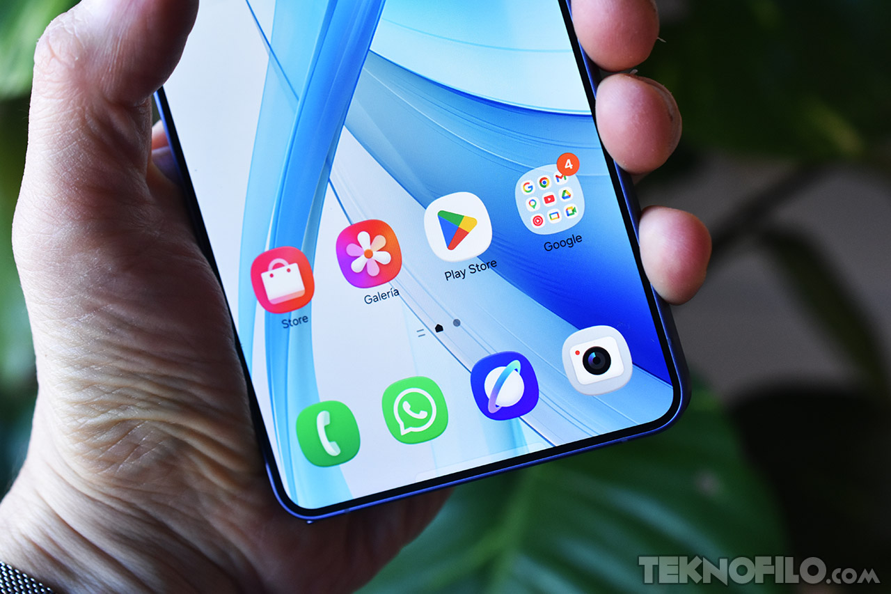 Pantalla de smartphone con aplicaciones como Play Store, Galería y WhatsApp en uso, sostenido por una mano.