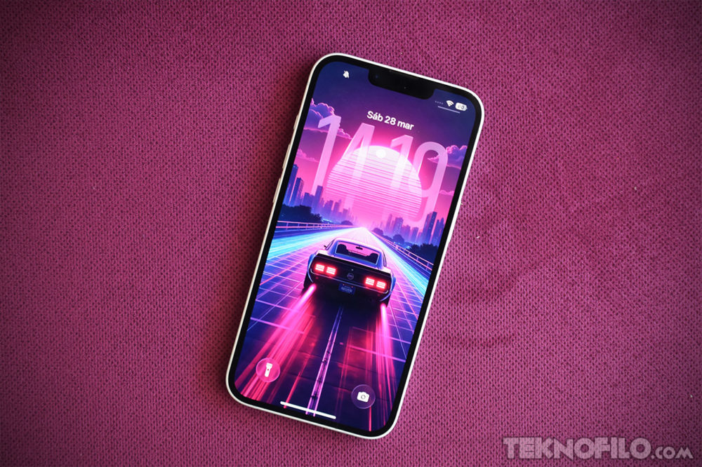 iPhone 18 Pro: las 6 grandes mejoras que prepara Apple para su próximo buque insignia iPhone con fondo de pantalla retro futurista de auto en carretera, sobre fondo rosa. Pantalla muestra el 28 de marzo.