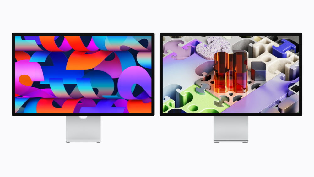 Studio Display y Studio Display XDR: Apple renueva su gama de monitores para el Mac Dos monitores con fondos coloridos abstractos y de rompecabezas, sobre bases plateadas.