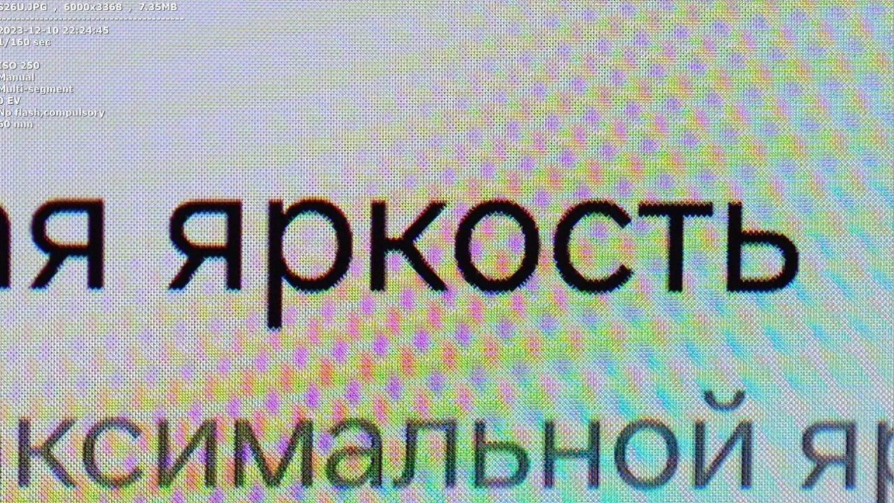 Texto pixelado en pantalla con letras en ruso, fondo de colores difuminados.