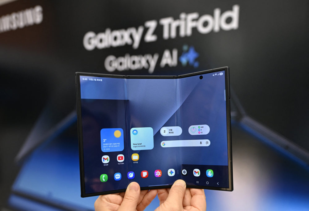 Smartphone Samsung Galaxy Z TriFold con pantalla desplegable en exhibición sobre fondo borroso.