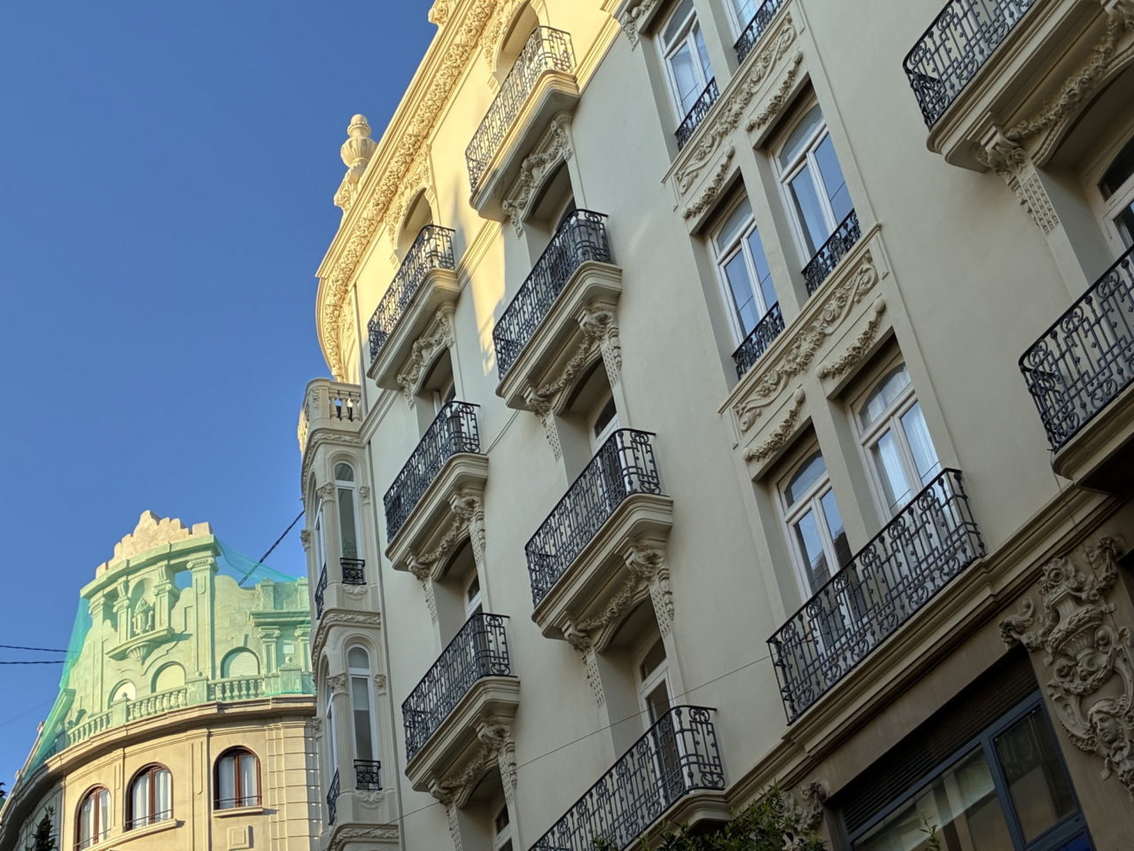 Edificios históricos con balcones de hierro forjado bajo un cielo azul en una ciudad europea.