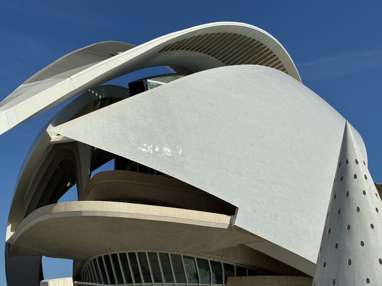 Arquitectura moderna del edificio en Valencia con formas curvas y textura blanca bajo un cielo azul.
