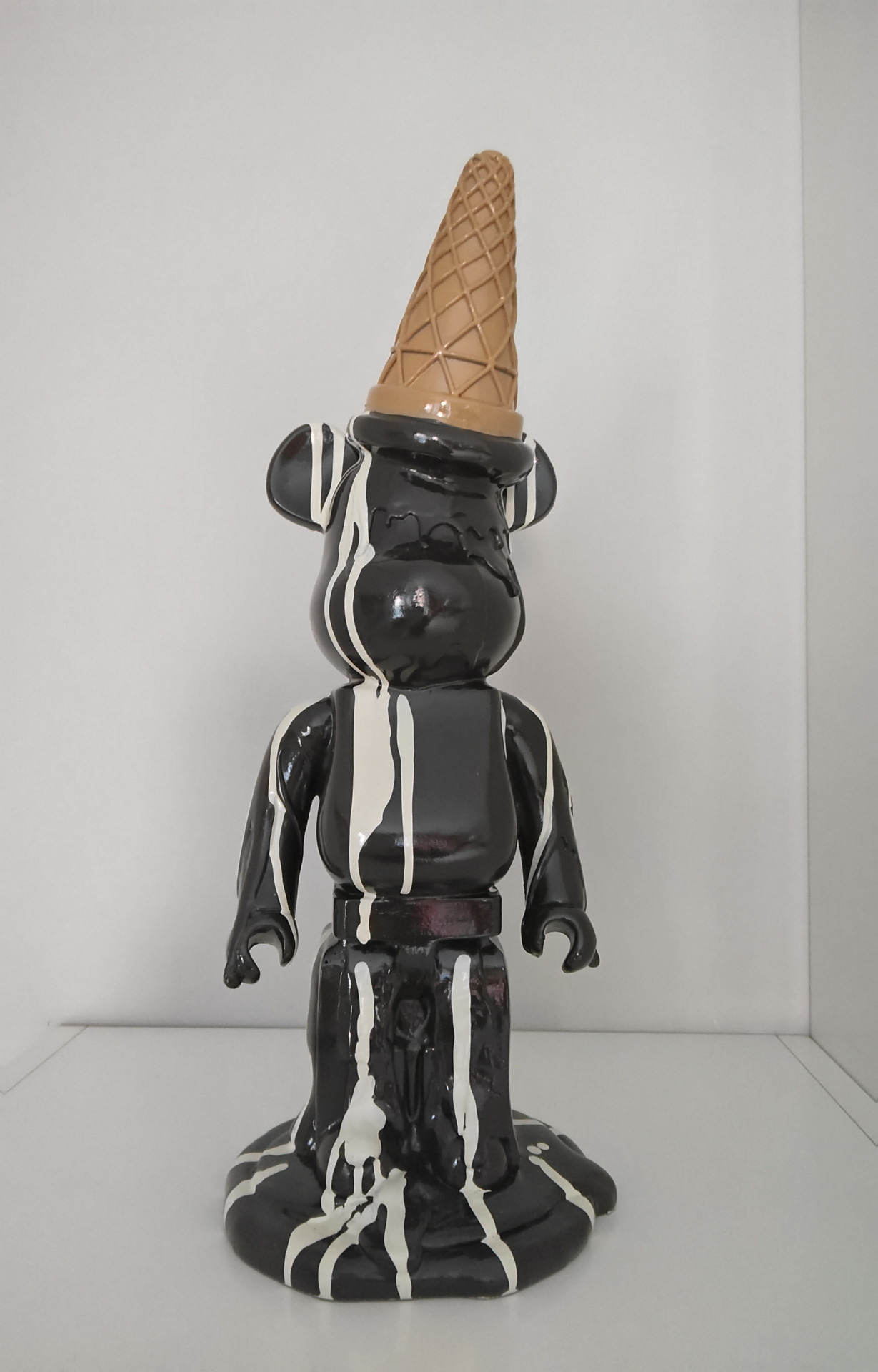 Figura de oso de vinilo derretido con cono de helado en la cabeza, decoración artística moderna en blanco y negro.