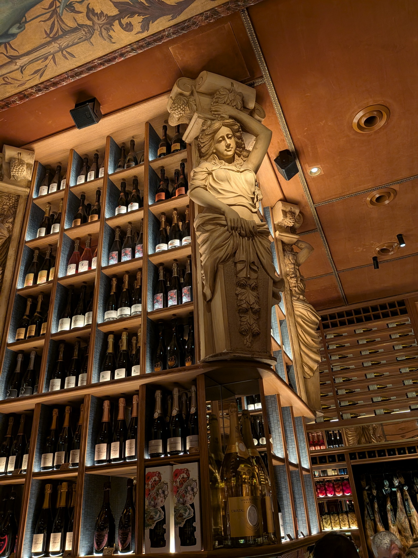 Estantería de vinos en un restaurante con decoración artística y esculturas. Ambiente elegante y sofisticado.