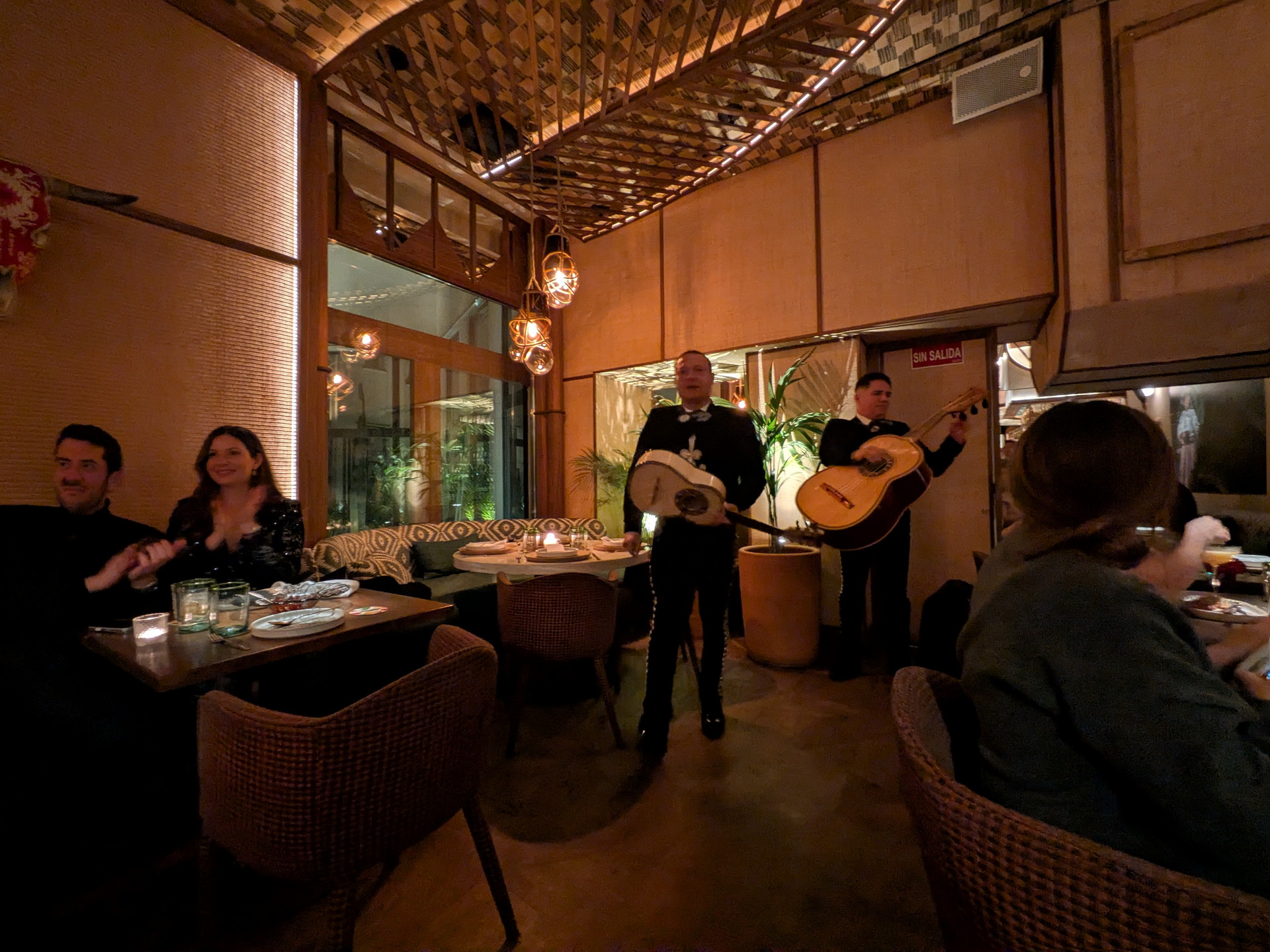 Mariachis tocando en un restaurante acogedor, con personas disfrutando de música en vivo y ambiente cálido.