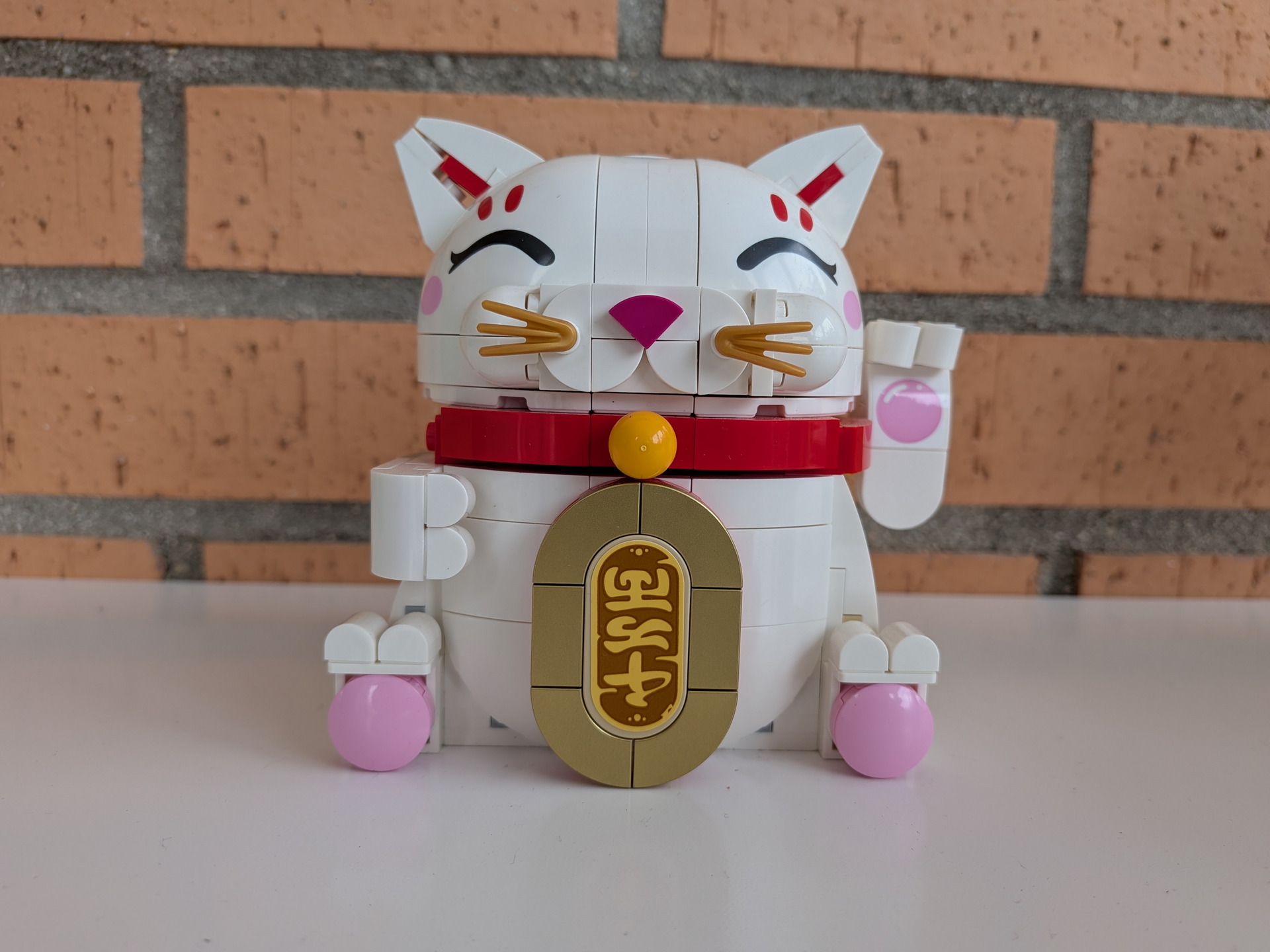 Figura de gato de la suerte hecho con bloques de construcción, fondo de ladrillos. Símbolo de buena fortuna.