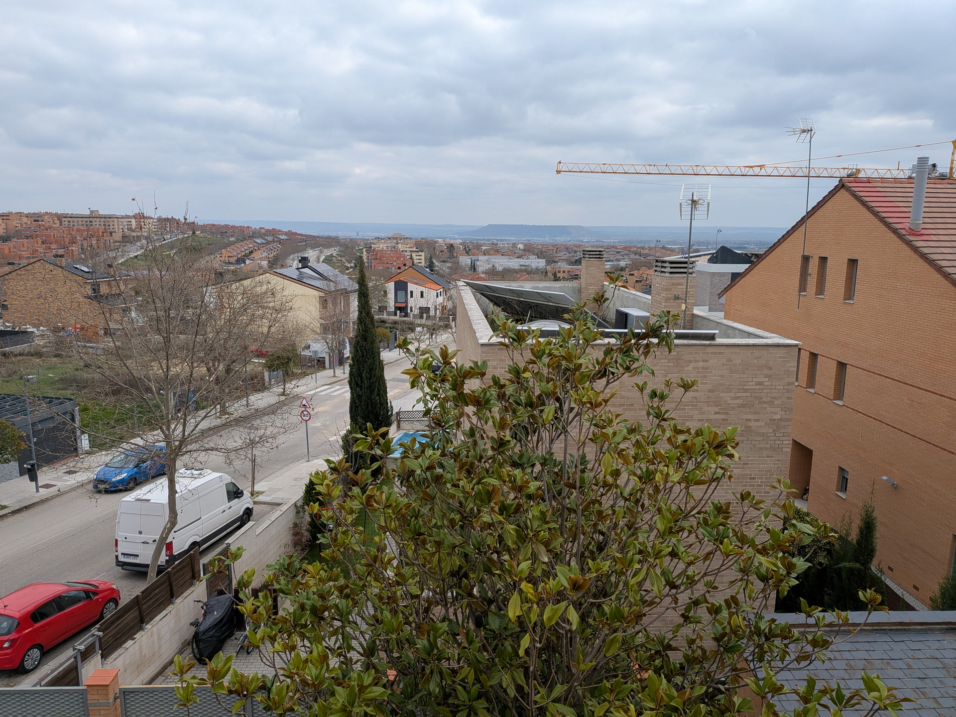 Vista urbana con edificios de ladrillo, árboles sin hojas y cielo nublado en un barrio residencial.