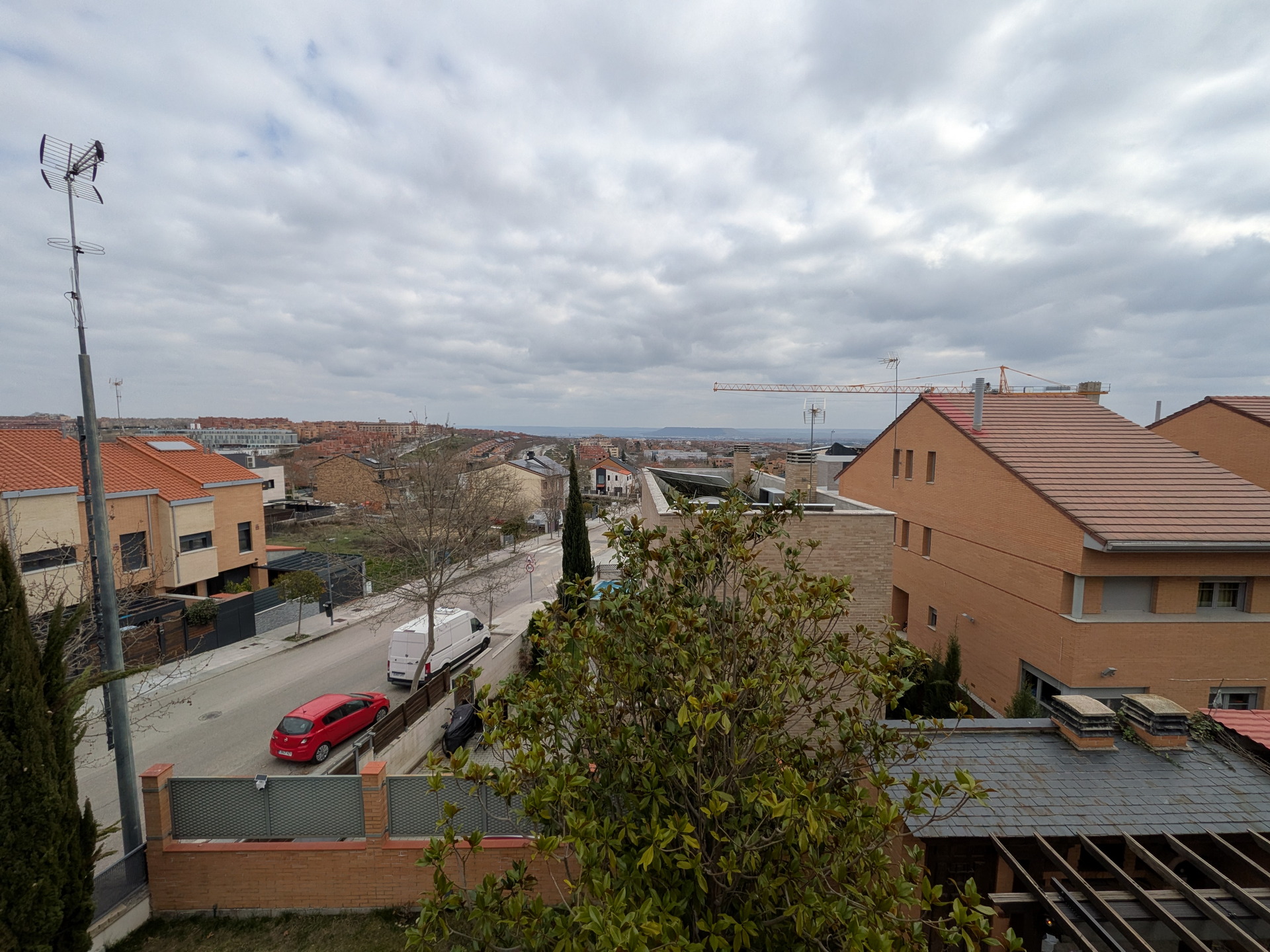 Vista panorámica de un barrio suburbano con casas, coches y cielo nublado; día nublado en zona residencial.