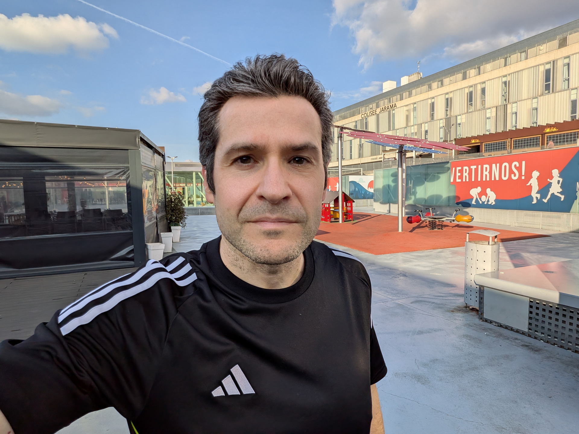 Persona en cancha deportiva al aire libre con cielo azul y edificio de fondo. Ambiente soleado y relajado.