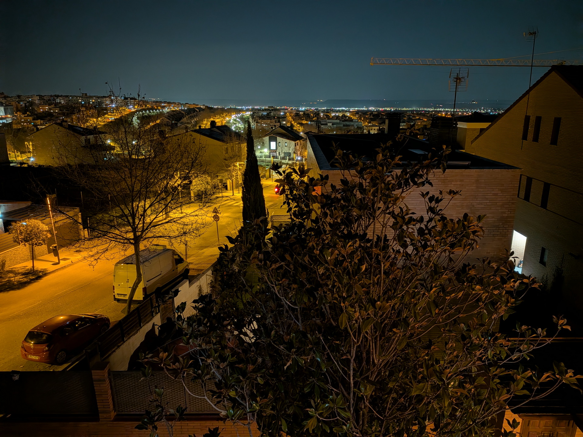 Vista nocturna de una ciudad iluminada, con calles y edificios visibles, capturando el ambiente urbano silencioso.