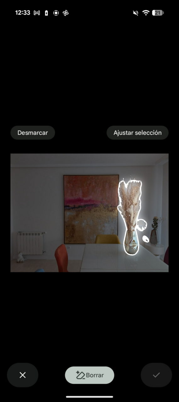 Mesa comedor con jarrón de hierbas secas y cuadro abstracto de fondo en salón moderno.