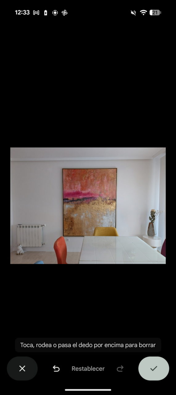 Pintura abstracta en sala de estar moderna con sillas de colores y mesa blanca. Ambiente minimalista y luminoso.