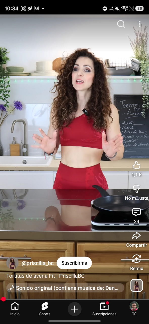 Cocinera en ropa deportiva roja comparte receta de tortitas de avena en cocina moderna con sartén en encimera.