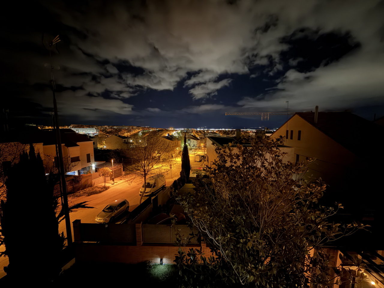 Vista nocturna de barrio residencial iluminado con nubes en el cielo, crea un ambiente tranquilo y sereno.