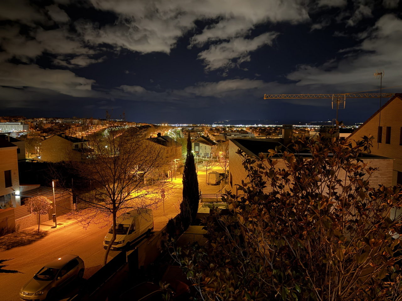 Vista nocturna de una ciudad iluminada, con cielo nublado y calles tranquilas. Ideal para paisajes urbanos.