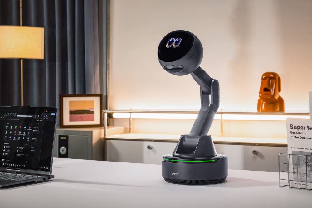 Lenovo AI Workmate Concept: el asistente con proyector que quiere revolucionar la oficina Asistente robótico futurista Lenovo en una oficina moderna con laptop y lámpara decorativa.