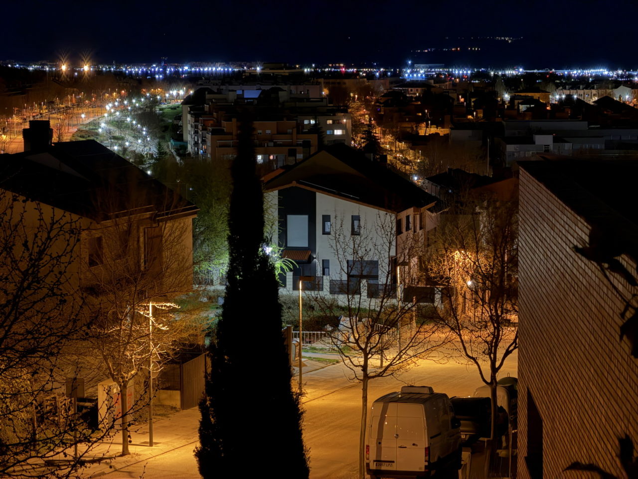 Vista nocturna de un barrio iluminado con luces callejeras y edificios, hogar de una comunidad urbana.