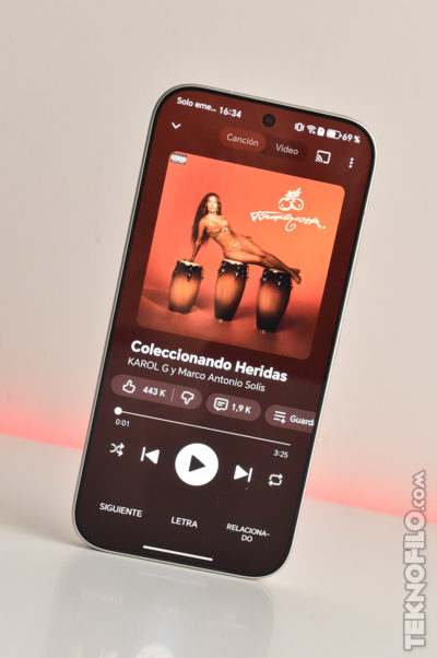 Smartphone mostrando canción Coleccionando Heridas de Karol G y Marco Antonio Solís en aplicación de música.