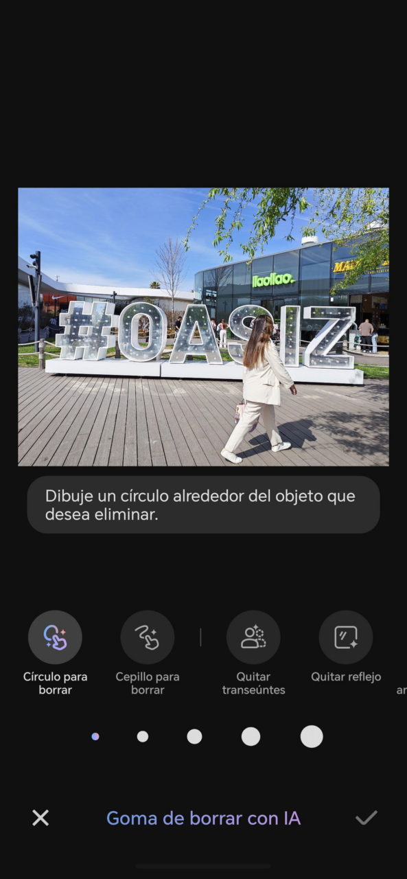 Mujer caminando frente a letrero gigante de Oasiz en un centro comercial al aire libre.