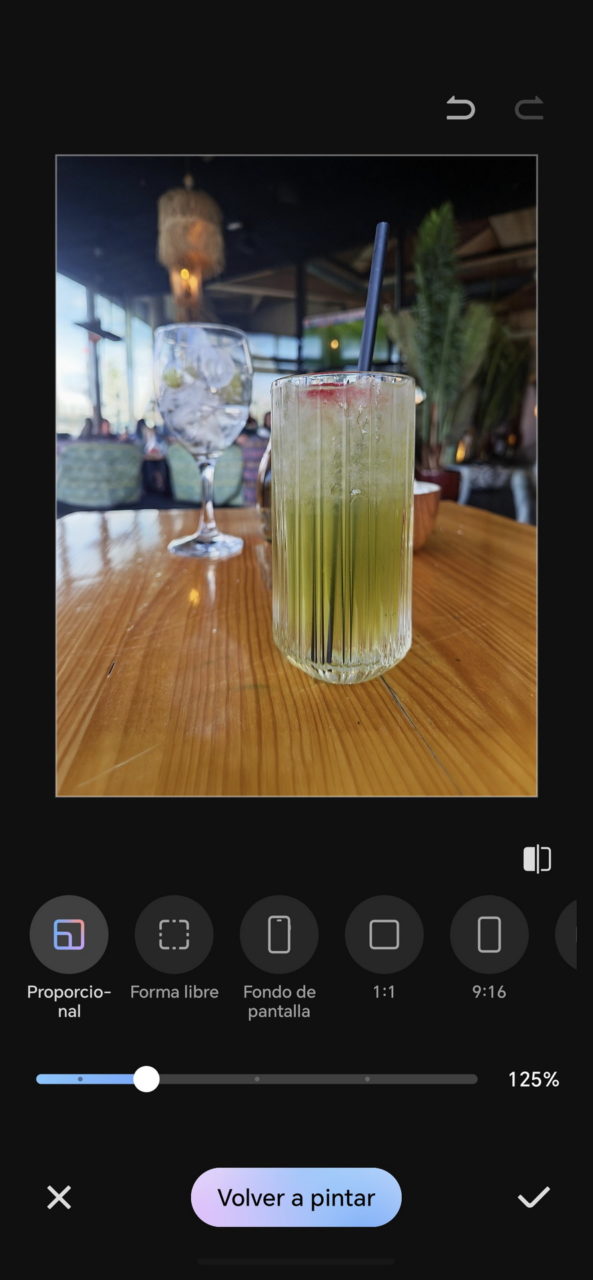 Cóctel fresco en vaso de cristal con pajita sobre mesa de madera en un restaurante elegante.