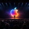 ¿Cuándo será el próximo evento de anuncio de Apple? Evento de Apple con logo iluminado en pantalla, público atento y presentador en el escenario. Tecnología e innovación.